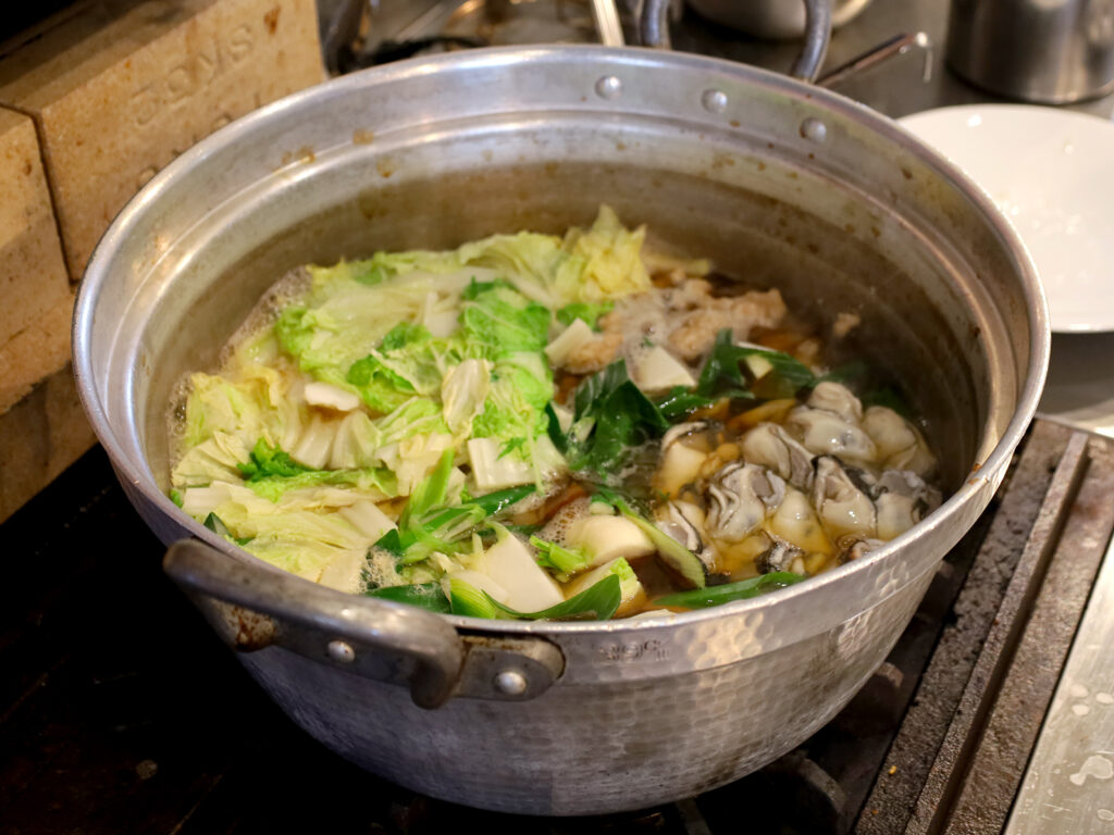 スープができたら、豚肉や牡蠣、野菜を入れて煮込み、最後に鯖を入れます。